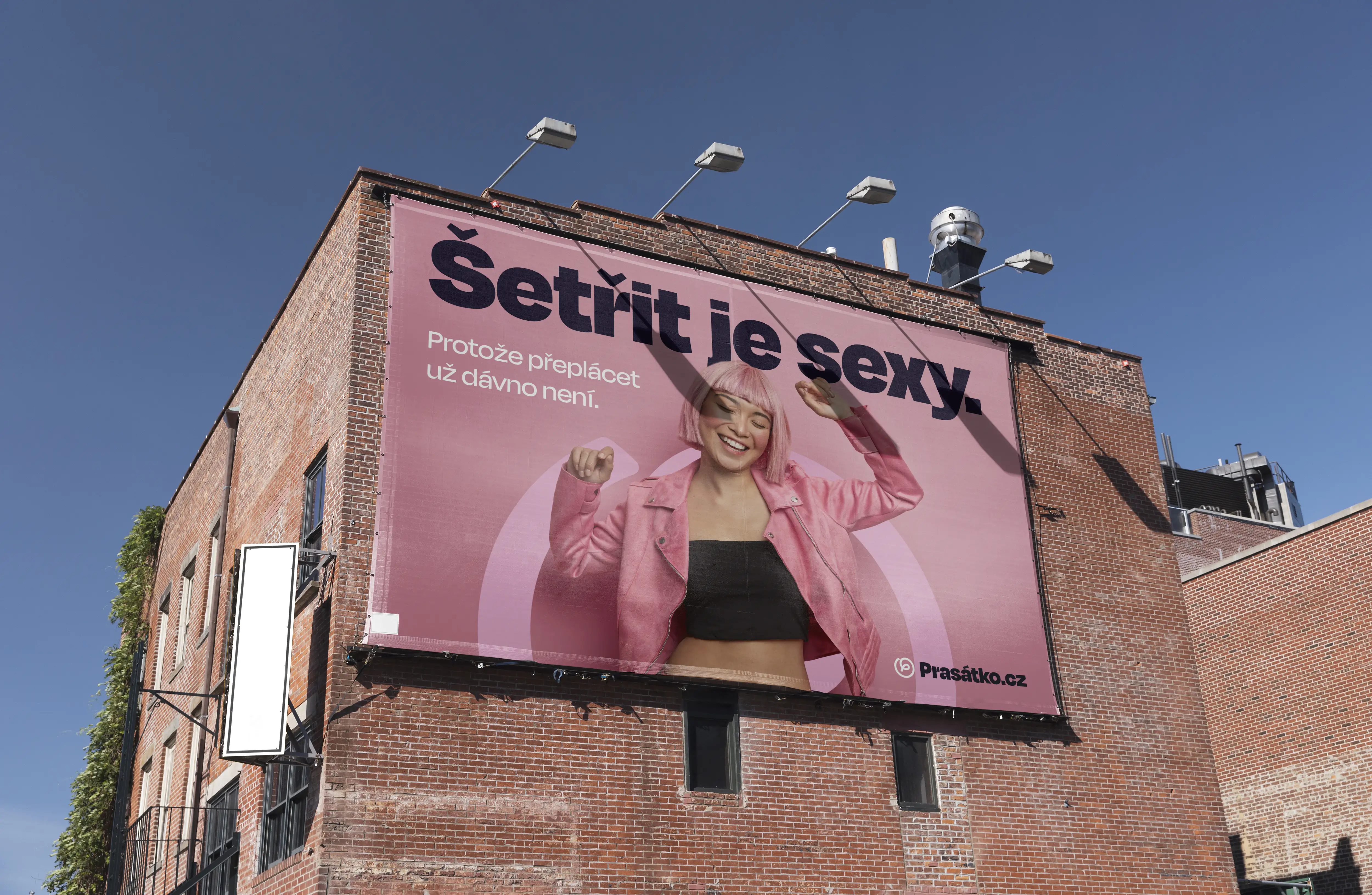 Billboard Prasátka s nápisem Šetřit je sexy na cihlové budově